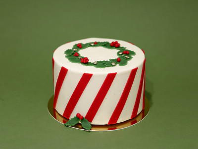 Gâteau de Noël Merry Christmas, avec décors rayés rouge et blanc et feuilles de houx réalisés par Chez Bogato.