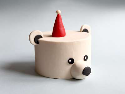 Gâteau de Noël en forme d'ours polaire avec une petit bonnet rouge, avec un décor réalisé à la main en pâte d'amande.