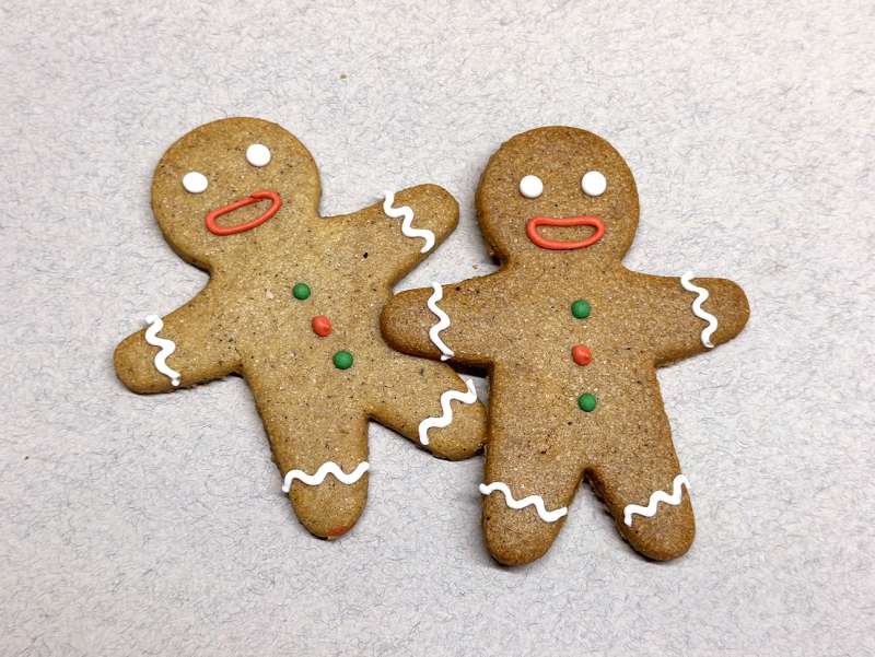 Sablé Gingerman avec décor réalisé à la main, avec un pull de Noël dessiné avec des petits points rouges et verts.