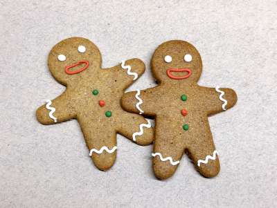 Sablé Gingerman avec décor réalisé à la main, avec un pull de Noël dessiné avec des petits points rouges et verts.