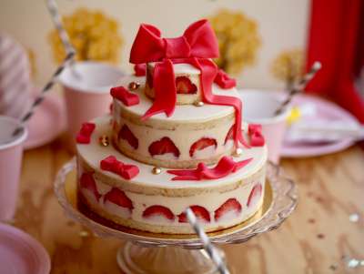 Chalala rouge de trois étages, en fraisier avec noeud et ruban rouge en décor pâte d'amande