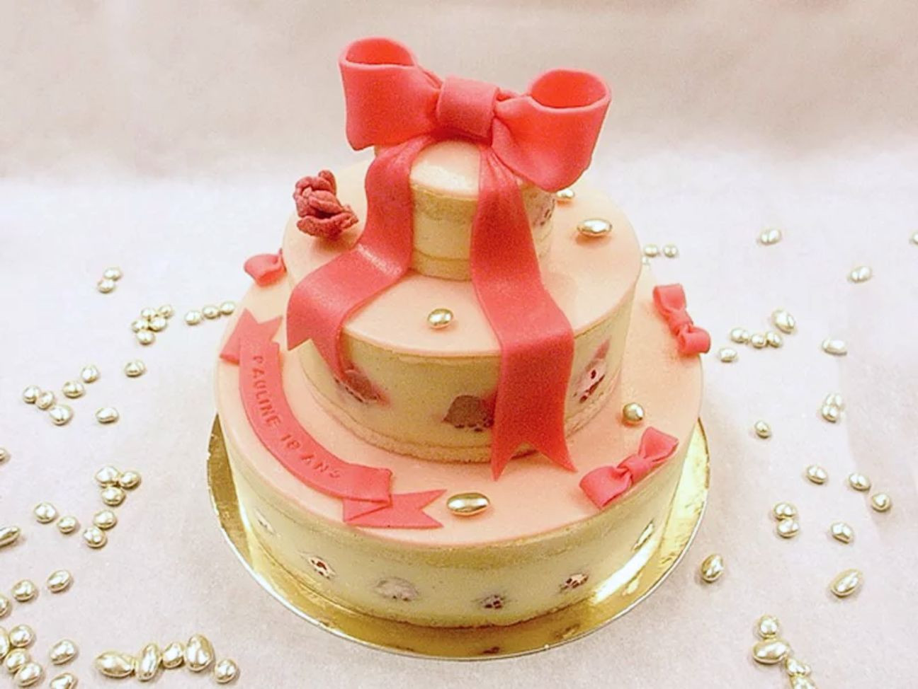 Gâteau Chalala de trois étages avec ruban et noeud rose, recette framboise et rose