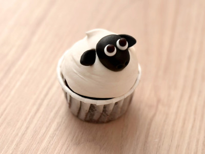Cupcake en forme de mouton, crème blanche et tête noire en pâte d'amande.