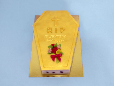 Gâteau en forme de cercueil doré, inscription RIP et fleurs - décoré à la main de la pâtisserie Chez Bogato.