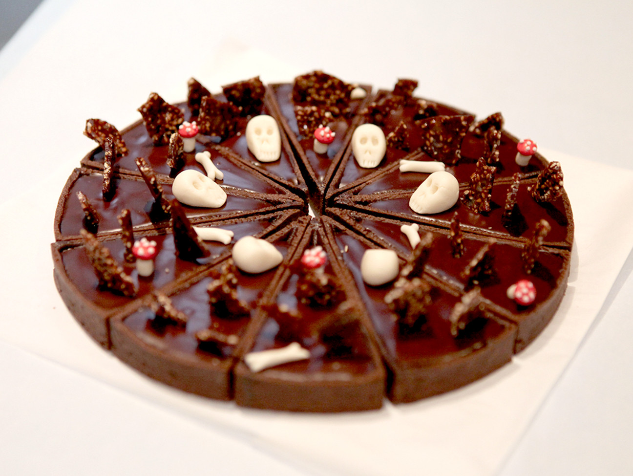Tarte au chocolat découpée en 12 parts et décorée avec des têtes de mort pour halloween