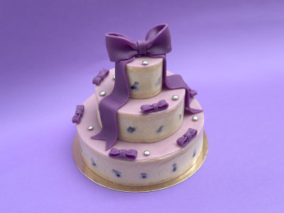 Gâteau chalala mauve sur trois étages à la myrtille & violette, avec ruban et petits noeuds violet