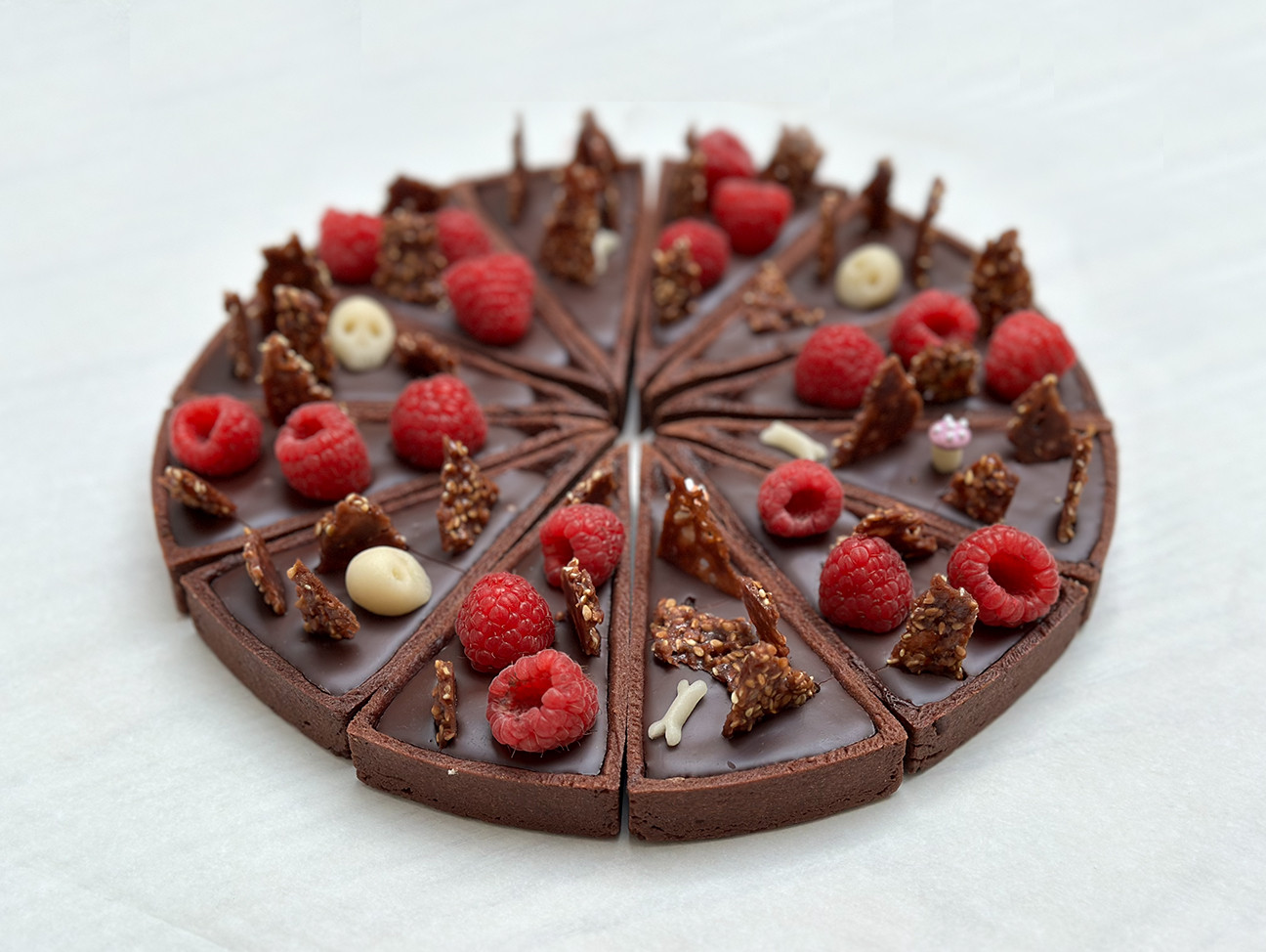 Tarte au chocolat découpée en 12 parts et décorée avec des têtes de mort pour halloween ou un vieil anniversaire