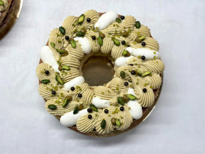 Tarte en forme de couronne avec croustillant pistache, praliné fondant pistache, ganache pistache et ganache chocolat.